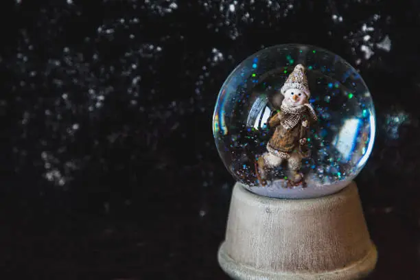 Photo of Glass ball with snow and snowflake on dark background