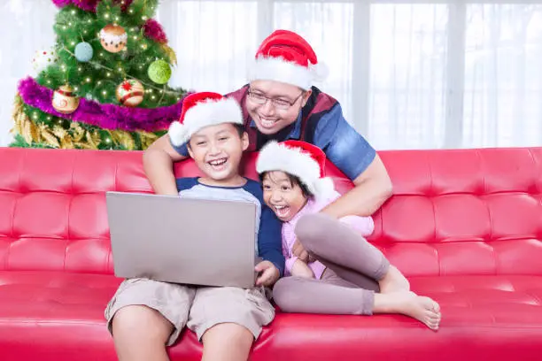 Young father and his children playing with a laptop while celebrating Christmas at home