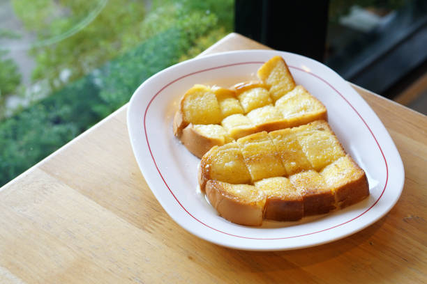 A plate of butter toast with condensed milk and sugar on wooden table.