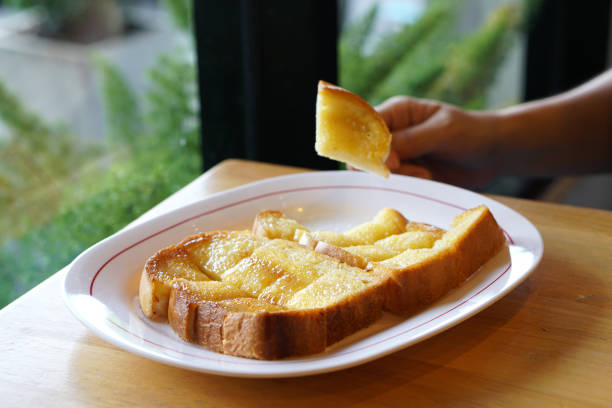 A plate of butter toast with condensed milk and sugar on wooden table.