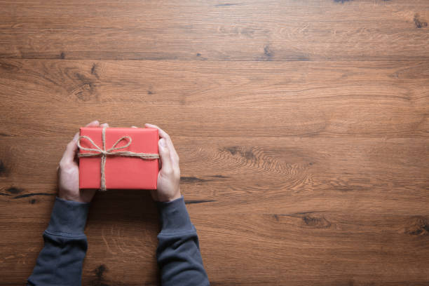 istock Man Hands holding craft paper gift box on table wood background and copy space. 892634398
