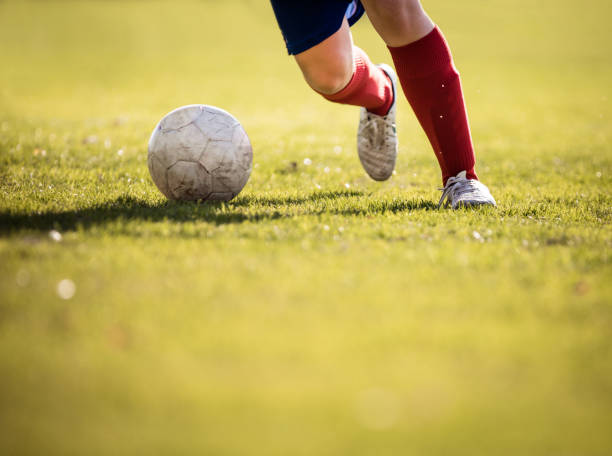 nicht erkennbare fußball-spieler läuft mit dem ball. - soccer shoe soccer player kicking soccer field stock-fotos und bilder