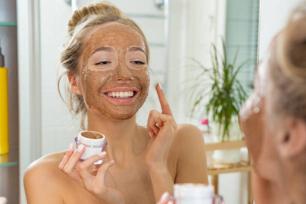 joven hermosa chica aplicar exfoliante facial mascarilla sobre la piel. - exfoliacion fotografías e imágenes de stock