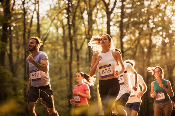 un grande gruppo di corridori motivati che corrono una maratona nella natura. - maratona foto e immagini stock