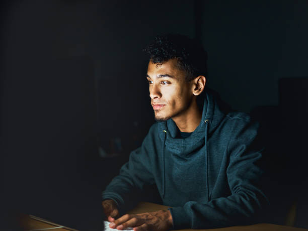 istock Young man using computer at night stares at monitor 892671002