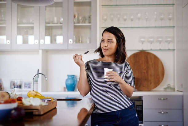 Enjoying spoonfuls of goodness Shot of an attractive young woman eating yogurt at home yogurt stock pictures, royalty-free photos & images