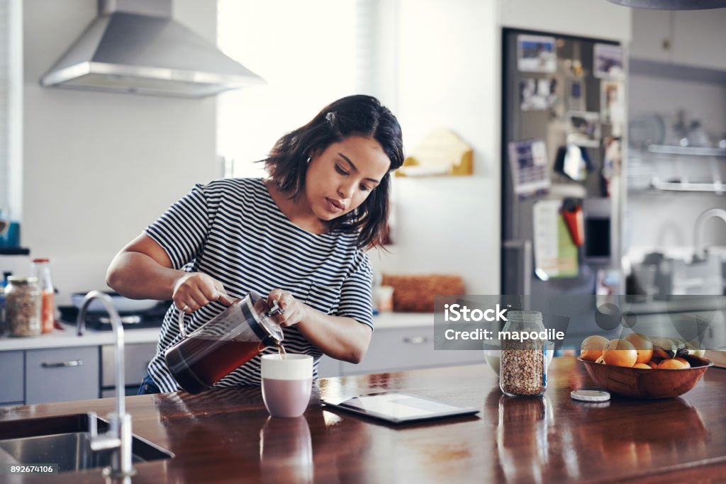 Today's breakfast is a fresh brew with a side of browsing Shot of an attractive young woman drinking coffee while using a digital tablet at home Coffee - Drink Stock Photo