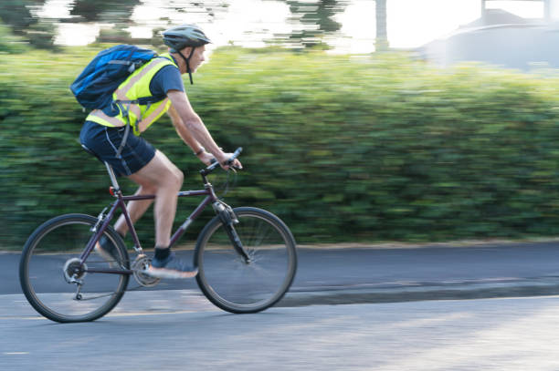 Cyclist in suburban street Cyclist riding past in suburban street Auckland New Zealand cycling vest photos stock pictures, royalty-free photos & images