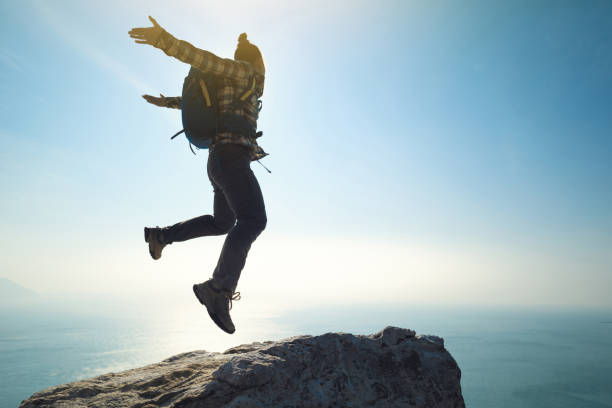 istock female hiker jumping on sunrise seaside cliff edge 892679102