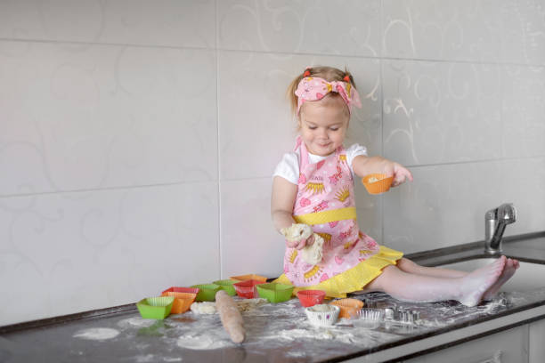 istock Little girl is cooking on kitchen. Having fun while making cakes and cookies. 892679448