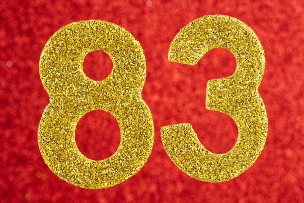 istock Number eighty-three yellow color over a red background. Anniversary 892687048