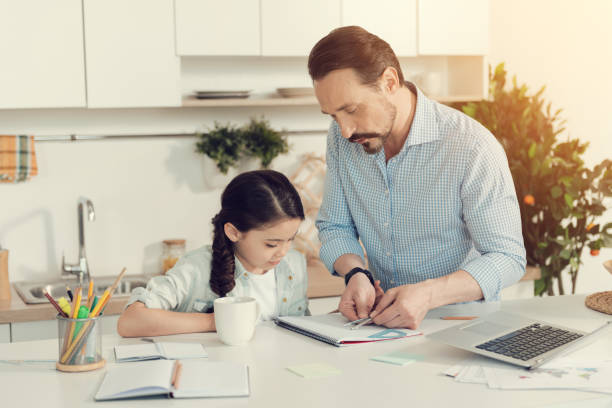 istock Smart nice man helping his daughter with homework 892691366