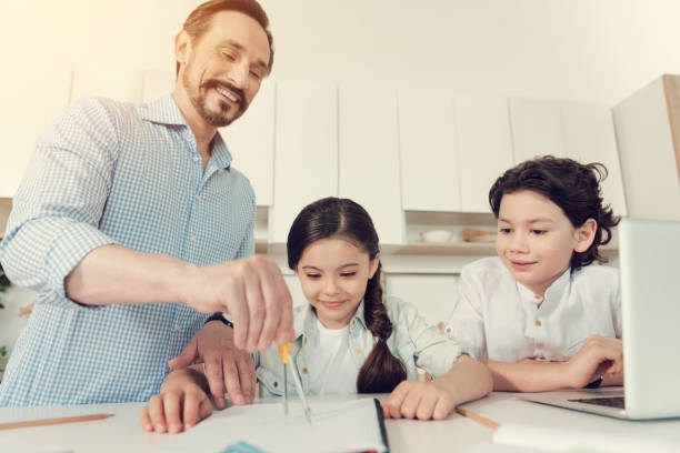istock Happy clever man helping his kids with homework 892693566