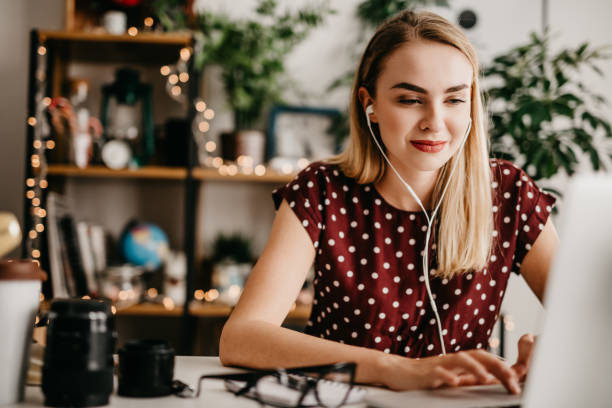 istock Woman with earphones doing editing on her video material 892701170