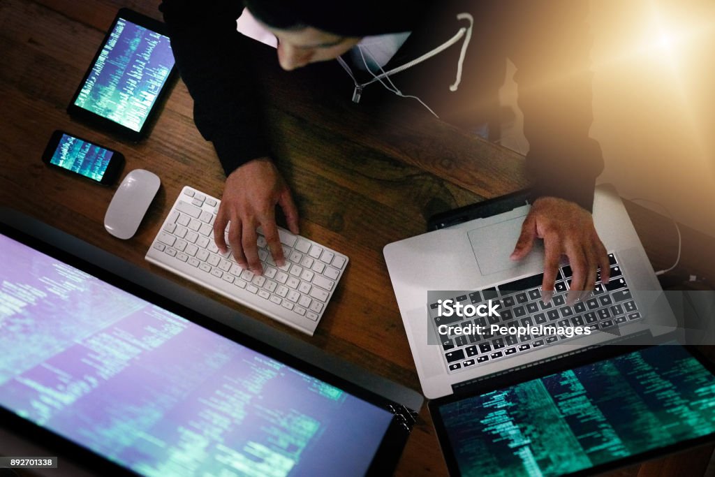 He knows how to exploit weaknesses in every cyber system High angle shot of a hacker cracking a computer code in the dark Internet Stock Photo