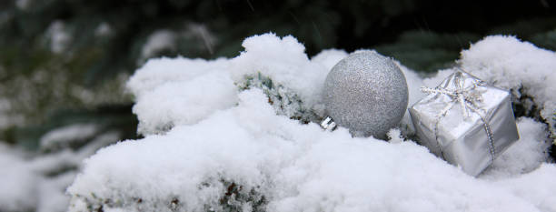 istock Silver christmas ball and present on white snow 892706952