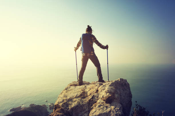 istock successful female hiker standing on sunrise seaside cliff edge 892711690