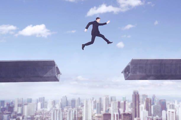 istock American businessman jumping over bridge gap 892717098