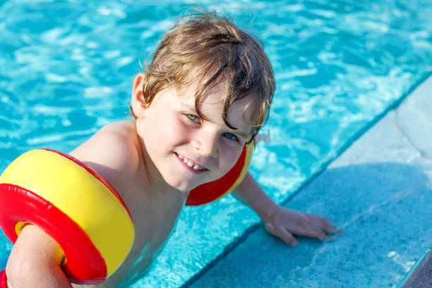 istock Happy little kid boy having fun in an swimming pool 892722820
