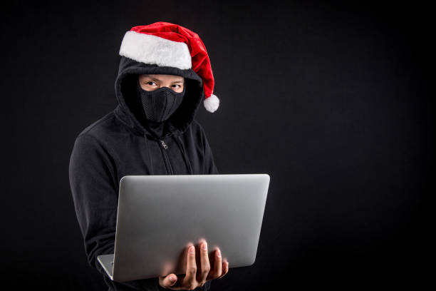 istock mysterious male santa hacker holding laptop computer 892726444