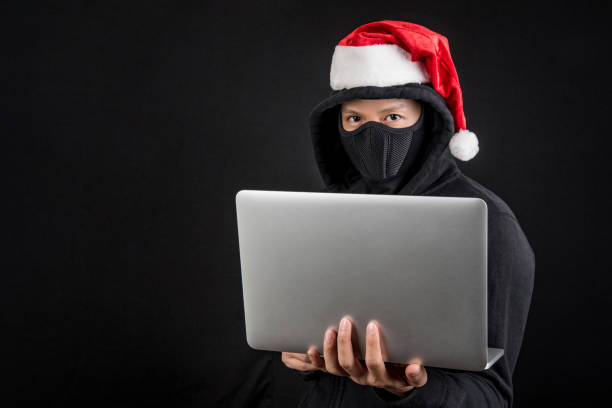 istock mysterious male santa hacker holding laptop computer 892728946
