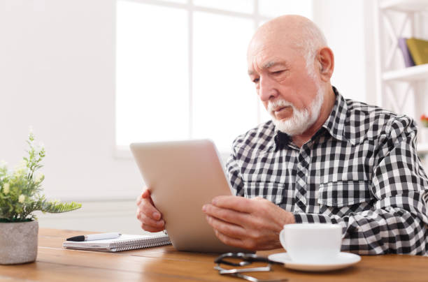 istock Senior man reading news on digital tablet 892729270