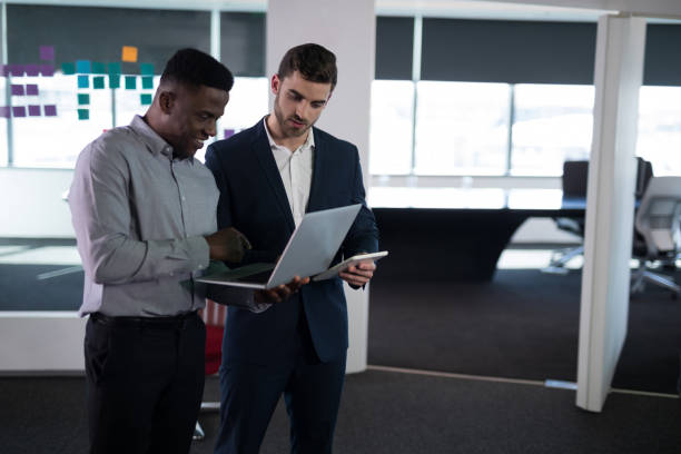 istock Happy male executives using laptop and digital tablet 892732242