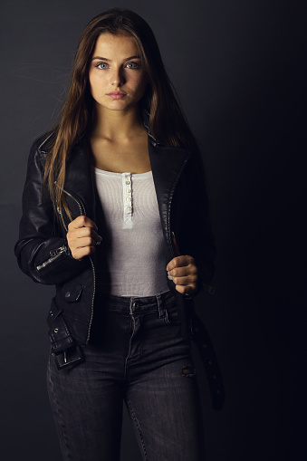 Beautiful teenage girl looking at camera . Fashion girl wearing a black leather jacket on studio