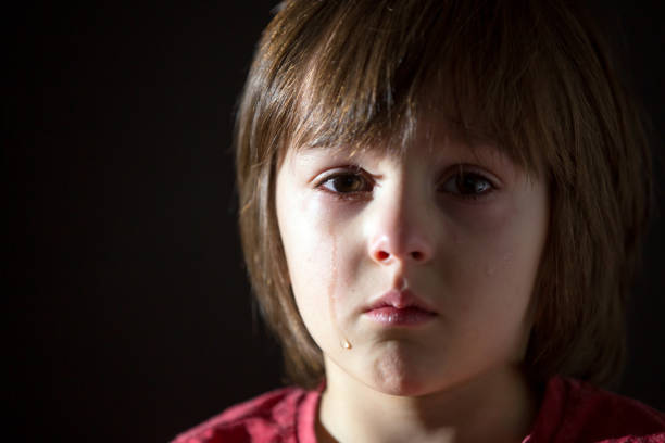 Boy in the blue T-shirt is snable and ready to cry. Red eyes.