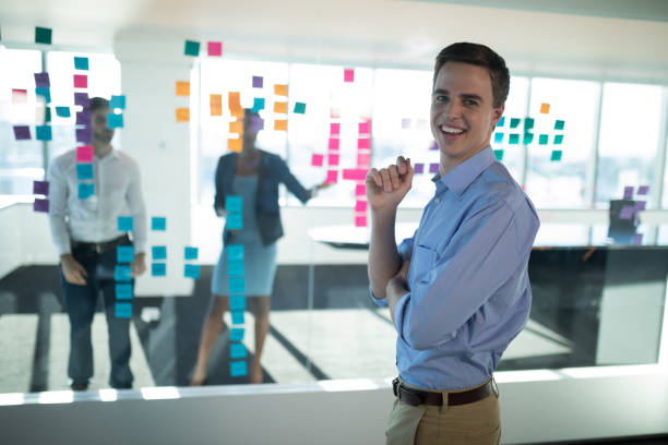 istock Male executive standing in office with colleagues in background 892739654