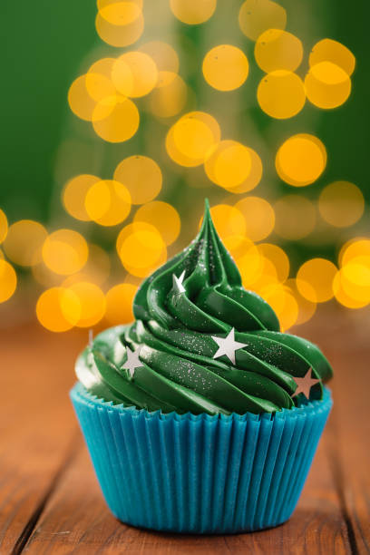 istock Green christmas cupcake with bokeh on background 892743048