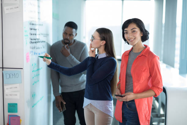 istock Female executive using mobile phone with colleagues in background 892748482