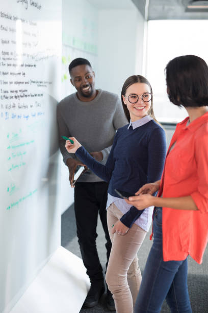 istock Male and female executives discussing on whiteboard 892748490