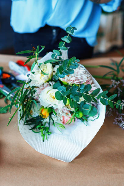 istock Charming cheerful female shop assistant making bouquet with Eucalyptus poplaraceous populus and Chrysanthemum single-headed Anastasia white 892779816