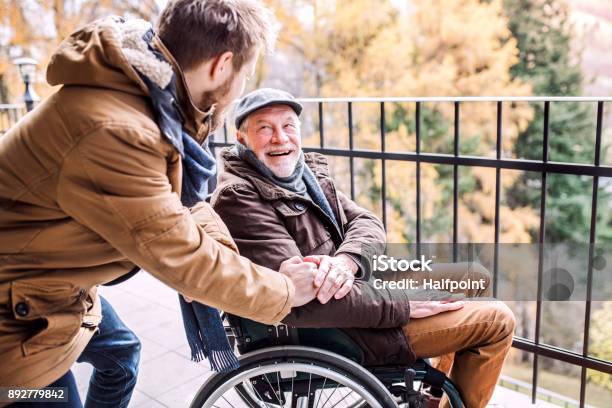 Senior Father In Wheelchair And Young Son On A Walk Stock Photo - Download Image Now