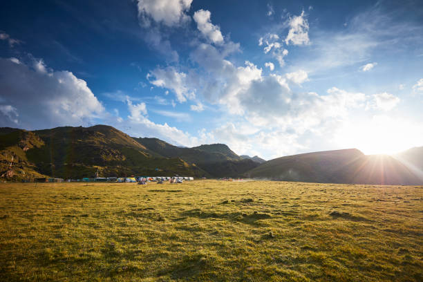Mt Elbrus base camp with tents in the sun with the mountains and partly cloudy sky in the background