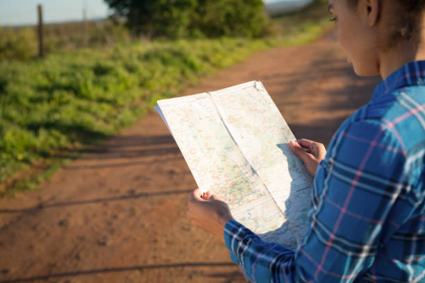 istock Woman holding a map standing on dirt track on a sunny day 892787028