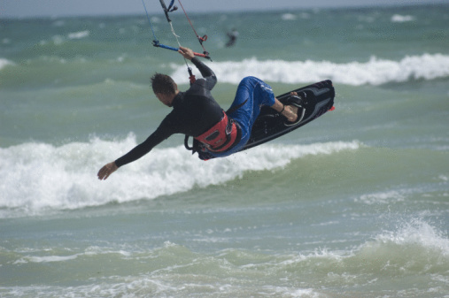 Kite Surfer jumping one handed mid rotaion (back loop transition)