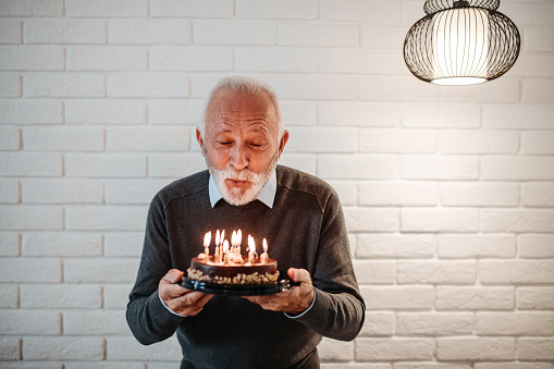Elderly man blowing out birthday candles