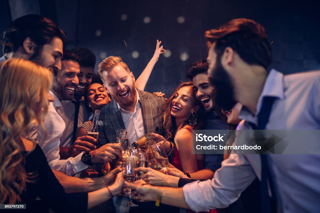 Top up the champagne Group of friends celebrating at the nightclub Party - Social Event Stock Photo