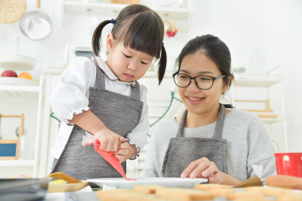 istock Asian Kid and young mother decorating cookies. 892798048