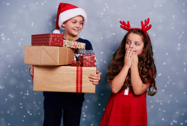 istock Happy siblings with stack of gifts among snow falling 892800350