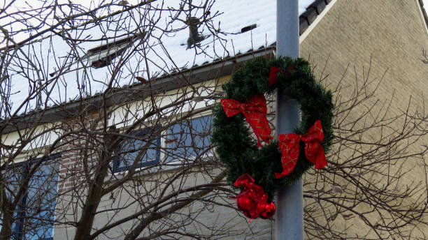 istock Christmas Wreath Hanging on Pole in Front of Snow Covered House 892804154
