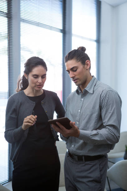 istock Colleagues discussing over digital tablet in waiting area 892812842
