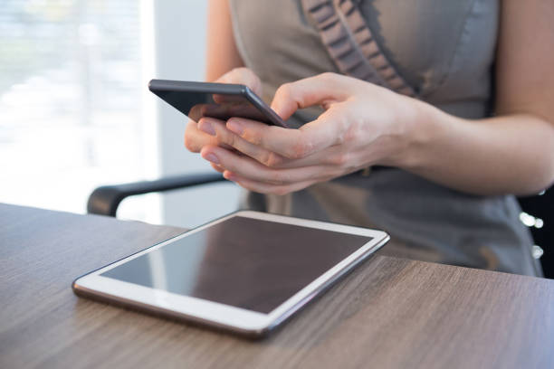 istock Mid section of female executive using mobile phone at table 892815712