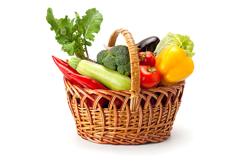 fresh and ripe vegetables arranged in a basket isolated on white