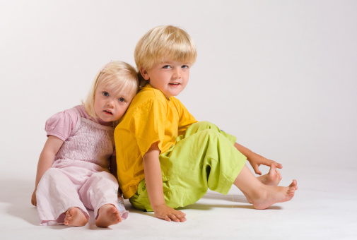 Upside down headshot of two brothers lying down on mattress without sheets and smiling