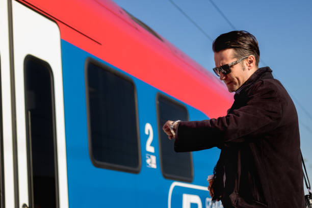 istock Businessman checking time on wristwatch at train station. 892818902