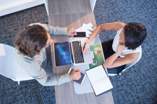 istock High angle view of business executives discussing over laptop 892821396