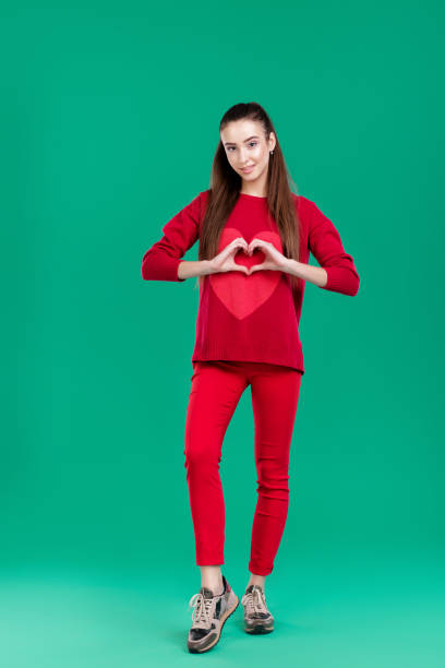 istock woman in red sweater on green background 892827520